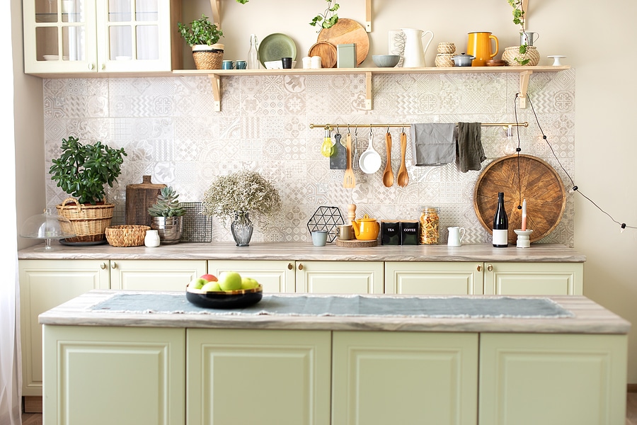 Stylish kitchen interior featuring sage-colored lower cabinets, open shelving above with seasonally colored accents.