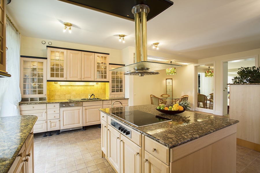 Horizontal view of spacious kitchen with marble worktop, central island, and white cabinetry.